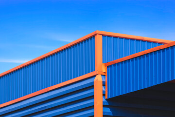 Blue and orange aluminium steel industrial warehouse building with louvered and roof awning against...