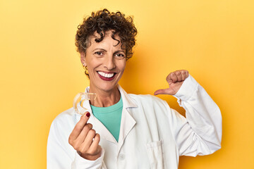 Doctor with invisible dental aligner on yellow feels proud and self confident, example to follow.