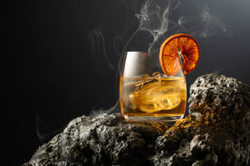Smoked old fashioned cocktail with ice and dried orange slice.