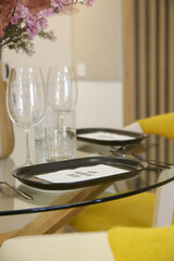 Dining table arrangement with ceramic black rectangular dinner plates, silver flatware set and glasses for water and wine.