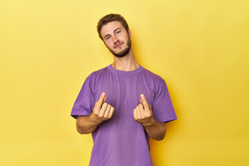 Young Caucasian man on a yellow studio background showing that she has no money.