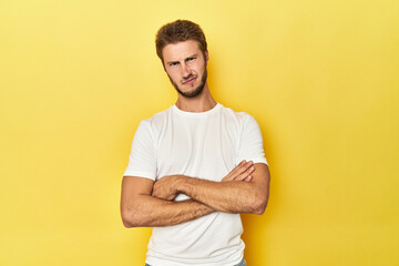 Young Caucasian man on a yellow studio background unhappy looking in camera with sarcastic...