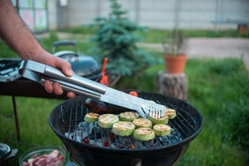 A man cooks grilled vegetables at a picnic in the garden at home. High quality photo