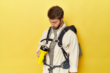 Mountain traveler with backpack and flashlight on yellow studio background