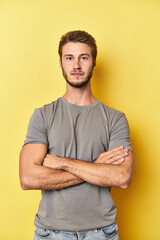 Young Caucasian man posing on a vibrant yellow studio backdrop