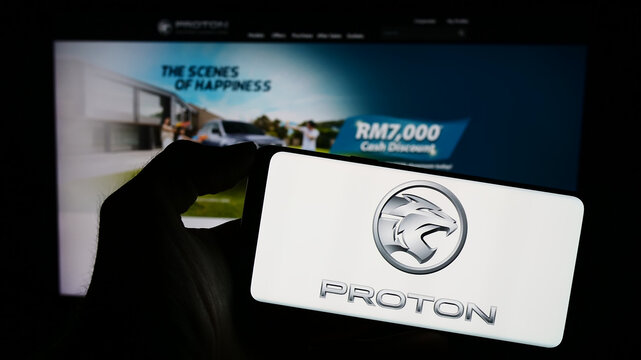 Stuttgart, Germany - 10-31-2023: Person holding cellphone with logo of Malaysian automotive company Proton Holdings Berhad (PHB) in front of webpage. Focus on phone display.