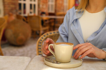 Cup of coffee on table and female hands, space for text