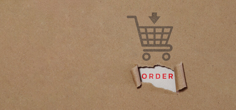 online shopping concept Shopping cart on brown cardboard background with order message on torn paper