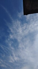 Photo of a bright blue sky with a few clouds like smoke