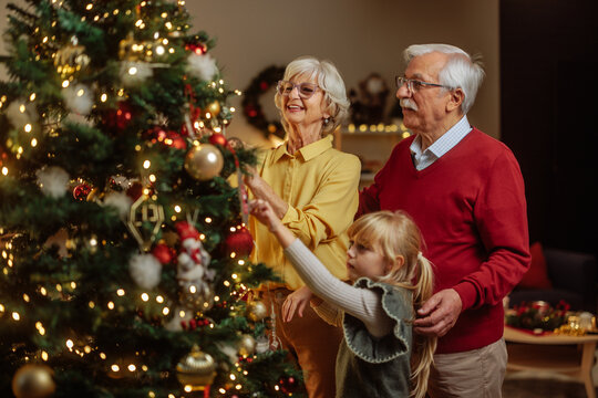 Grandparents and granddaughter decorating christmas tree