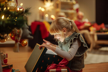 Cute little girl opening a mysterious Christmas present