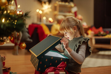 Little girl opening a mysterious Christmas present