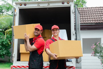 Indian and Caucasian partnership mover workers in red uniform uploading furniture and boxes to new...