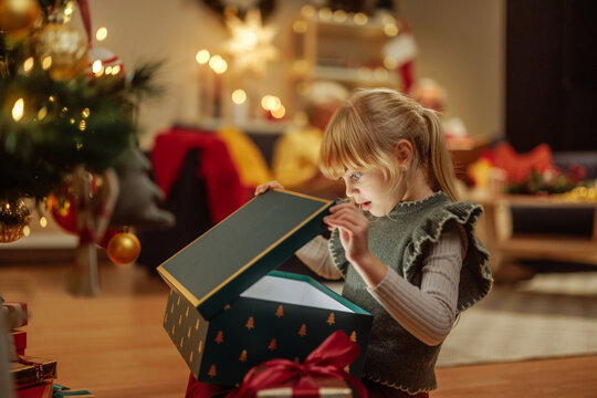 Little girl opening a mysterious Christmas present