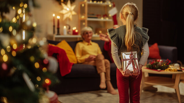 Little blonde girl hiding a Christmas present for her grandparents