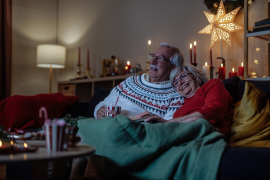 Older couple watching a movie during Christmas holidays while sitting on a sofa