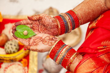Beautiful hands of an Indian woman with betel nut along with betel leaf performing puja rituals. Indian Hindu traditional background.
