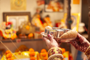 Beautiful hands of an Indian woman performing puja rituals with a plate of 'Prasadam'. Indian Hindu puja background.
