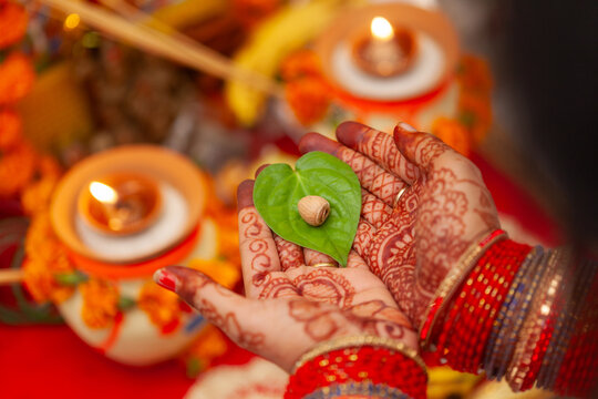 Beautiful hands of an Indian woman with betel nut along with betel leaf performing puja rituals. Indian Hindu traditional background.