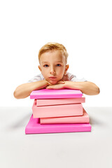 Cute little boy sitting at desk put his hands and head on stack of books. Child study and learn for preschool. Online education. Concept of childhood, International Knowledge Day, academic. ad