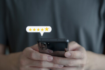Customer hand press on smartphone screen and give five star excellent rating for giving best score point to review the service, Customer experience, Evaluation, Satisfaction, Feedback, Review concept.
