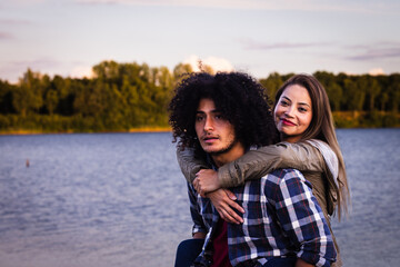 Happy biracial couple, love and hug laughing in joyful happiness for bonding time together in the outdoors. North African man and Asian woman enjoying playful fun piggyback with smile for holiday in