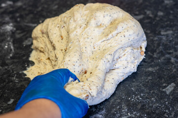 naan bread dough being kneaded by a chef with blue gloves