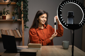 Female influencer recording video content at home, smiling woman unpacking box with new smartwatch...
