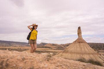 Naklejka premium Woman holding her hat because of wind in a desert
