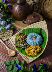 The blue colour of Nasi Kerabu comes from the petals of the butterfly pea flower. The rice is served with spiced shredded chicken and fried cassava leaves.