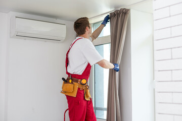 A male worker who installs a curtain.