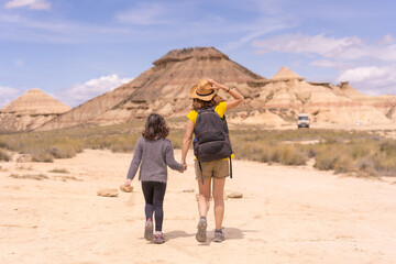 Rear view of mother and daughter walking along a desert