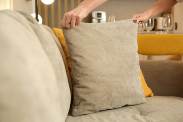 Woman arranging sofa cushion in living room	