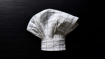 Chef hat on the dark table background.