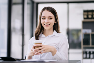 portrait of a business woman Self-confident young woman sit holding coffee mug and working laptop.  Casual business.