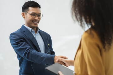 Happy businessman and businesswoman shaking hands at group board meeting. Professional business executive leaders making handshake agreement successful company trade partnership handshake concept.