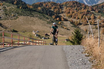 Female cyclist during ride.Woman cyclist wearing cycling kit and helmet riding on gravel bike.Cycling through stunning Romanian mountain landscapes.Good road for cycling.Cycling training on empty road