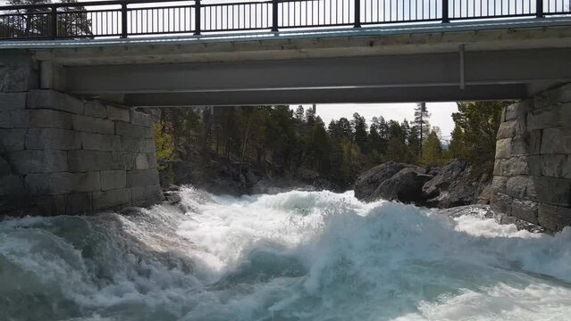 Srone footage following along fast flowing river, under bridge in Norway, Billingen