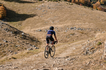 Male cyclist riding a gravel bike during sunny day in autumn mountains. Amazing autumn foliage....