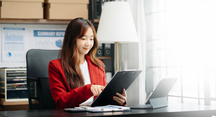 Young beautiful woman using laptop and tablet while sitting at her working place. Concentrated at...