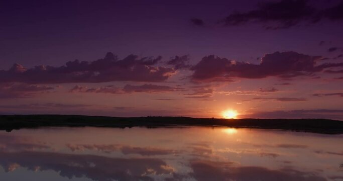 Sunrise on cloudy morning over calm lake in calm weather