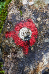 Closeup view of red hiking trail marker on the stone surface. Walking and sport activity and nature theme