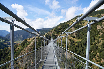 View of a Tibetan bridge from the inside with people walking on it in the background surrounded by...