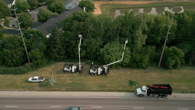 Safety tree trimming by work crew from company to keep tree limbs from encroaching on the electrical power lines. Wide aerial shot
