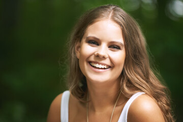 Portrait, smile and a woman in the forest on a green background for freedom, travel or to relax. Face, beauty and a happy young person in the countryside or woods for wellness or stress relief