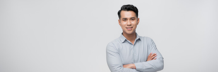 Positive young asian male looking away with smile while standing against white background