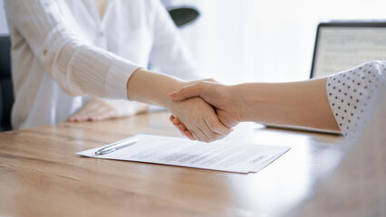 Business people shaking hands above contract papers just signed on the wooden table, close up. Lawyers at meeting. Teamwork, partnership, success concept - obrazy, fototapety, plakaty