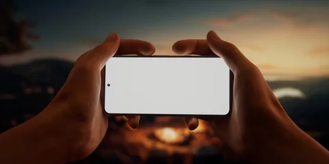 Selbstklebende Fototapeten Schokoladenbraun CU Caucasian male using his phone near campsite in the evening, screen mockup  © ivanbaranov