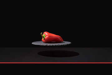 Pimiento rojo sobre un plato de pizarra y fondo negro