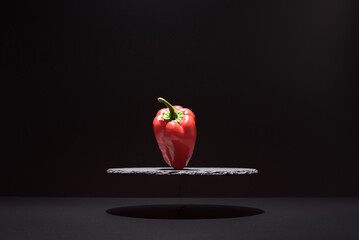 Pimiento rojo sobre un plato de pizarra y fondo negro